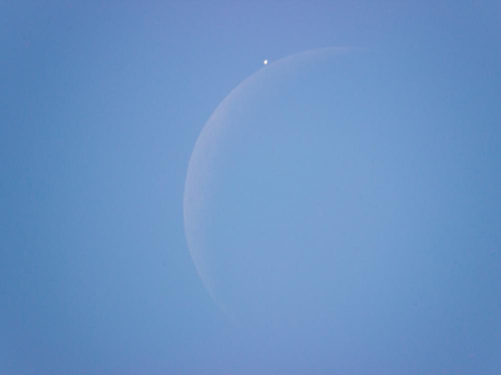 View of the daytime sky as the Moon is just about to block the view of Venus.