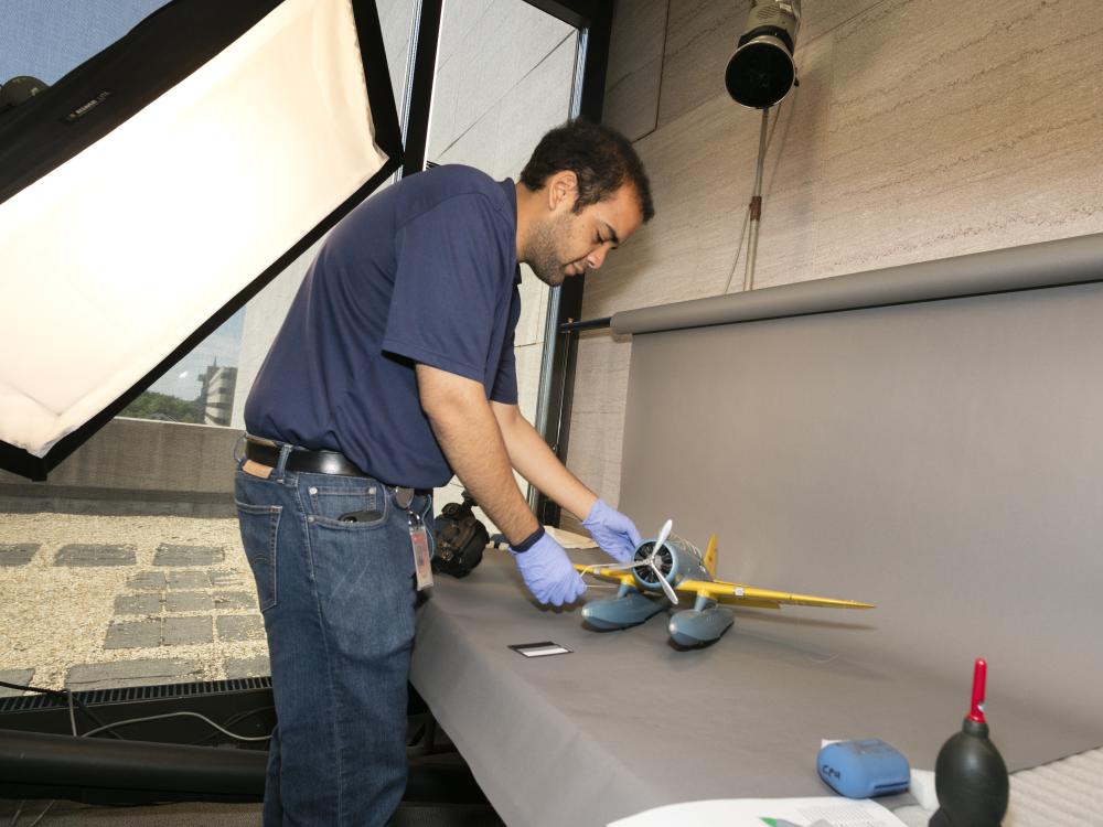 A Museum photographer moves an aircraft model prior to taking photos of the model.