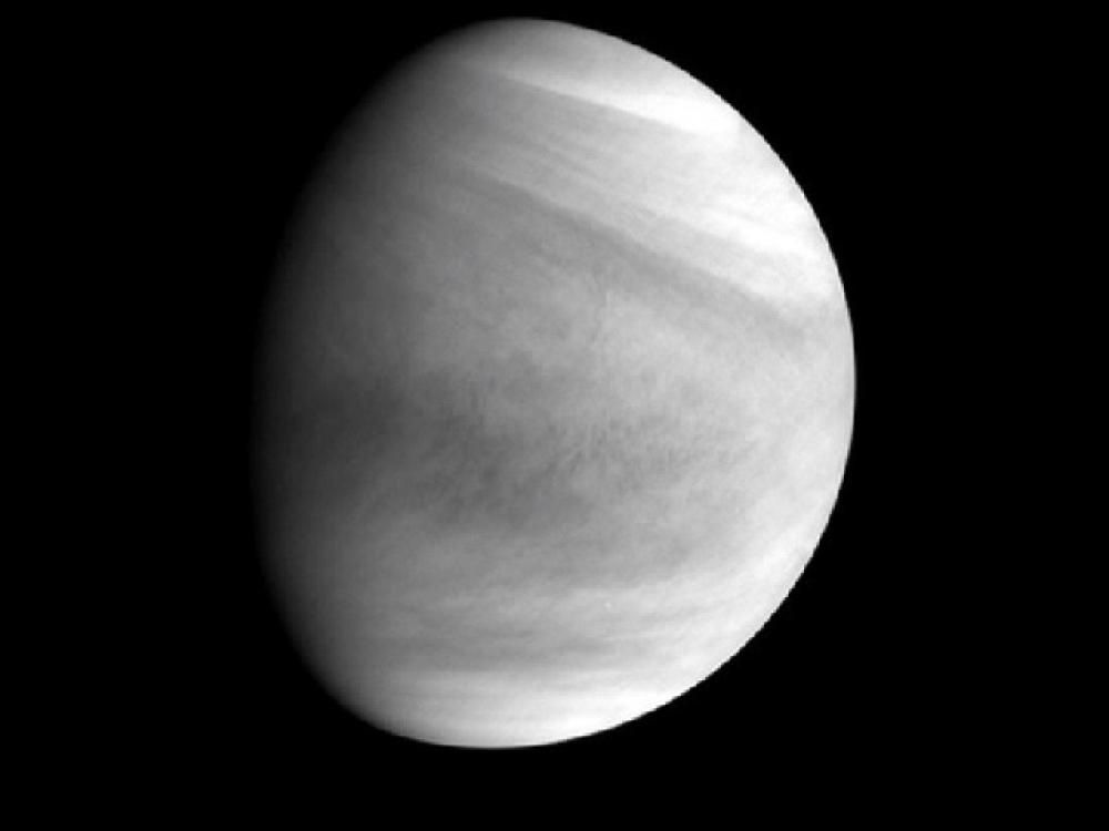 Partial disk view of Venus, with the sun reflecting on part of the planet. The reflection gives it a gibbous appearance.