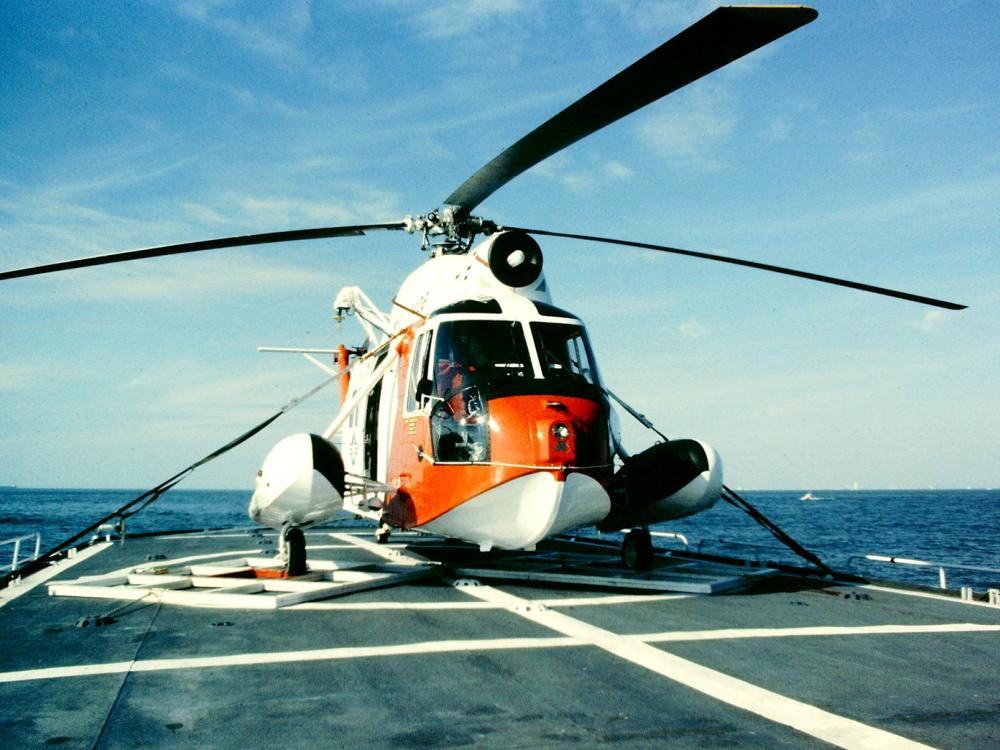 Front view of orange and white Coast Guard helicopter with three-blade rotor.