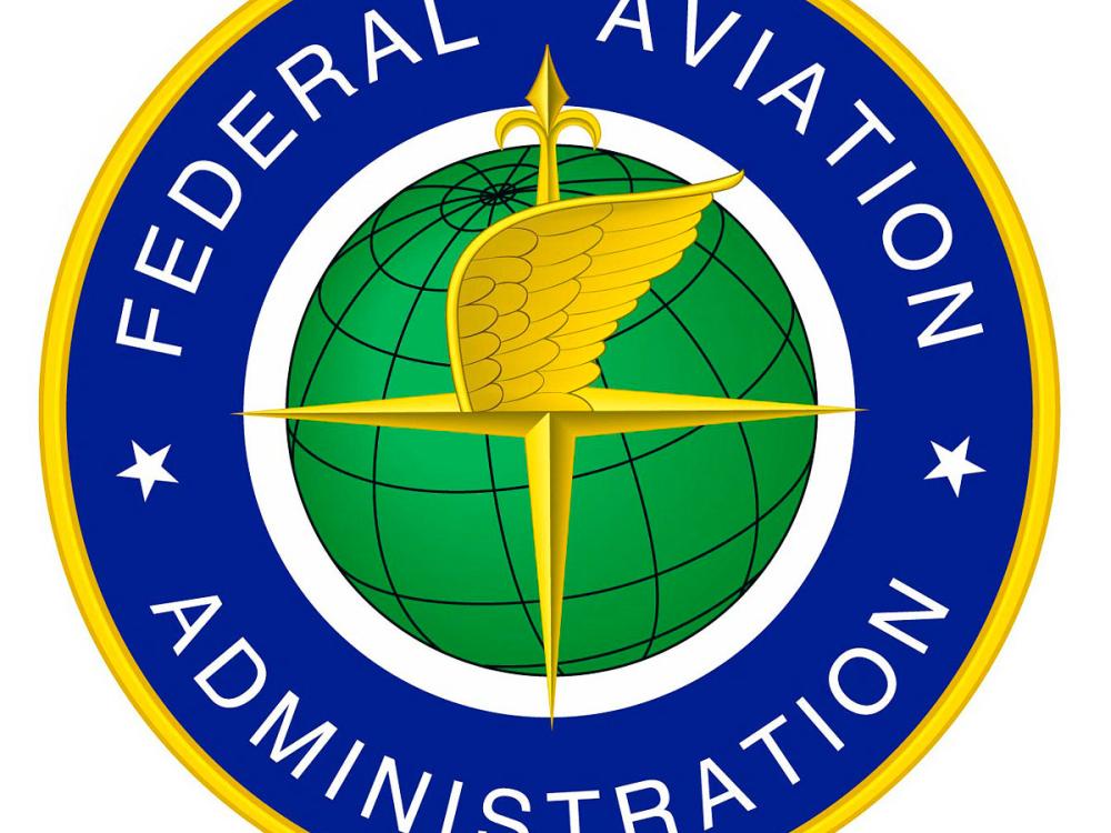 Federal logo featuring a blue and yellow circle surrounding a green globe with the compass arrow and a wing on the center. "Federal Aviation Administration" is stated in the blue and yellow circle in white.