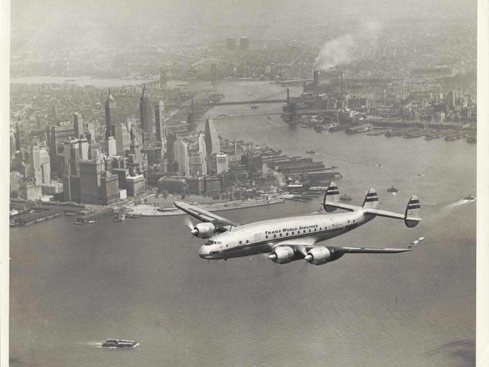 View of commercial aircraft in flight near a city.