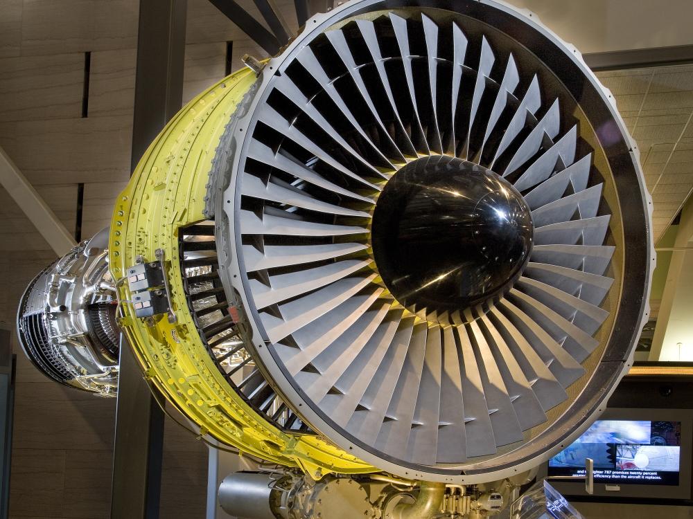 Front view of turbofan engine with large number of blades circling around a black, metal center.