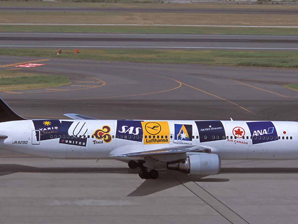 Side view of a commercial aircraft with multiple airline logos on the side of the aircraft.