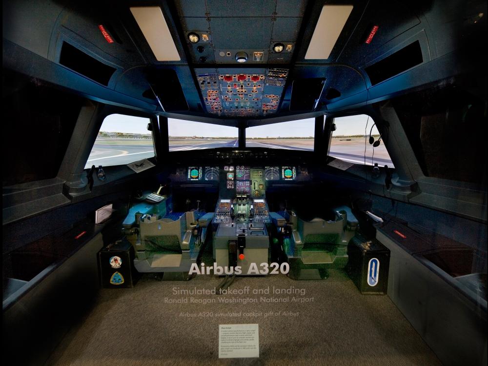 Glass display of the cockpit of a large commercial aircraft. A landscape is simulated in the windows of the cockpit.