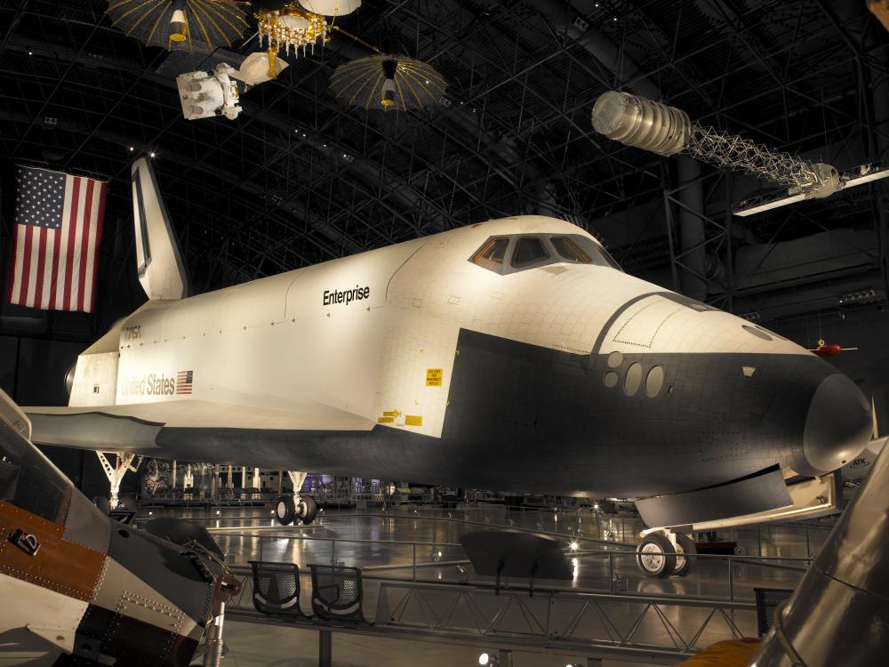 Side view of white and black space shuttle on display at the museum.