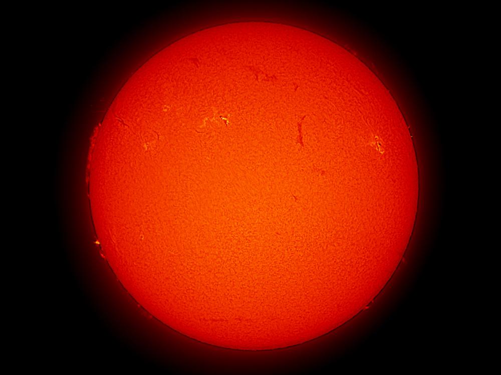 Disk view of the Sun with two visible sunspots and a large prominence of plasma rising from the Sun's surface on the left side of the disk.