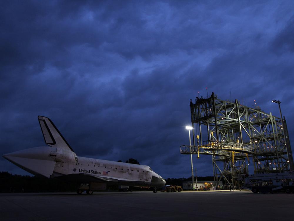 The Space Shuttle Discovery sits prior to being secured onto an aircraft via a large securing object known as a mate-demate device.