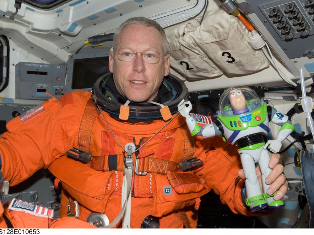 Patrick G. Forrester, an astronaut, holds a Buzz Lightyear figure in his hand while aboard a space shuttle.