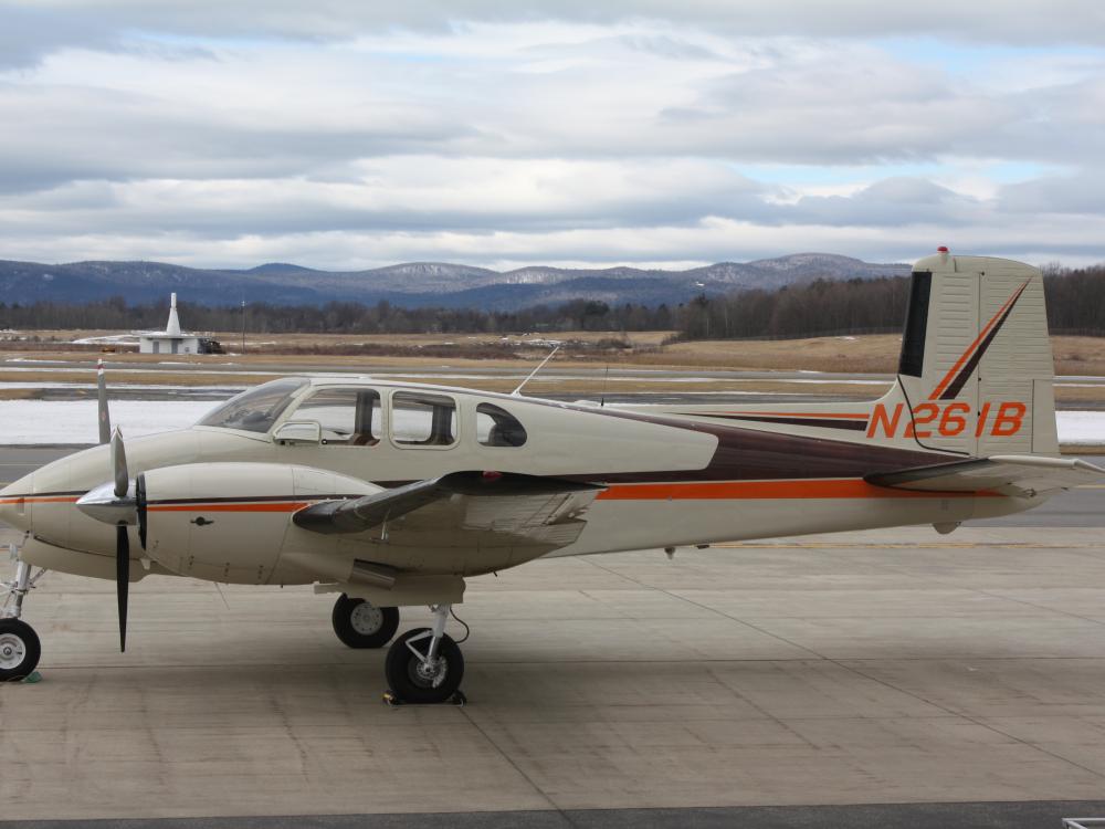 Side view of tan aircraft with orange and brown accent colors and two engines. Registration number N261B is painted in orange on the vertical stabilizer.