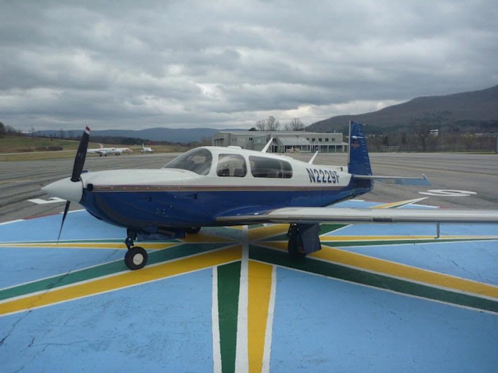 Side view of white and blue airplane with one propellor attached to the nose. The registration number N2229F is painted on the side of the plane near the rear of the fuselage.