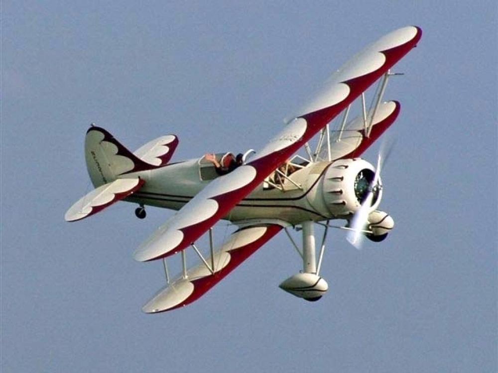 Side view of white and red biplane in flight with single engine.