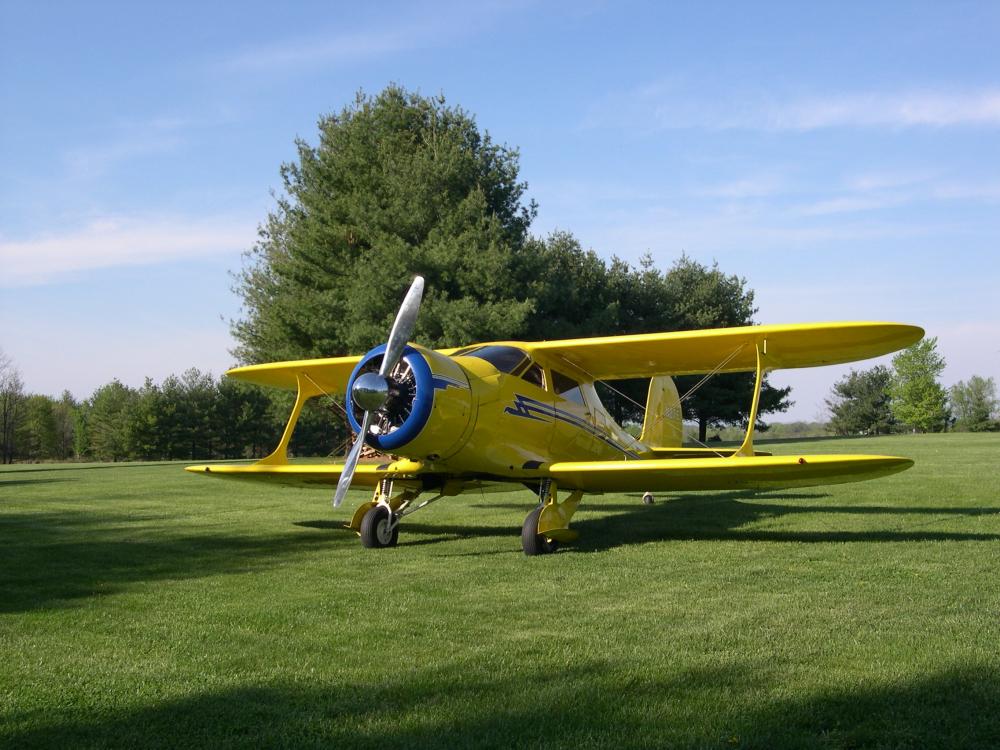 Frontal view of yellow biplane with single engine.