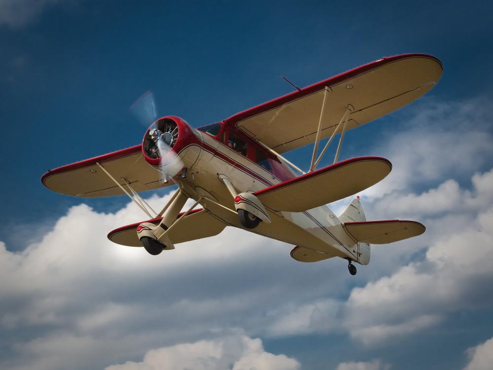 Bottom view of red and tan biplane with one engine.