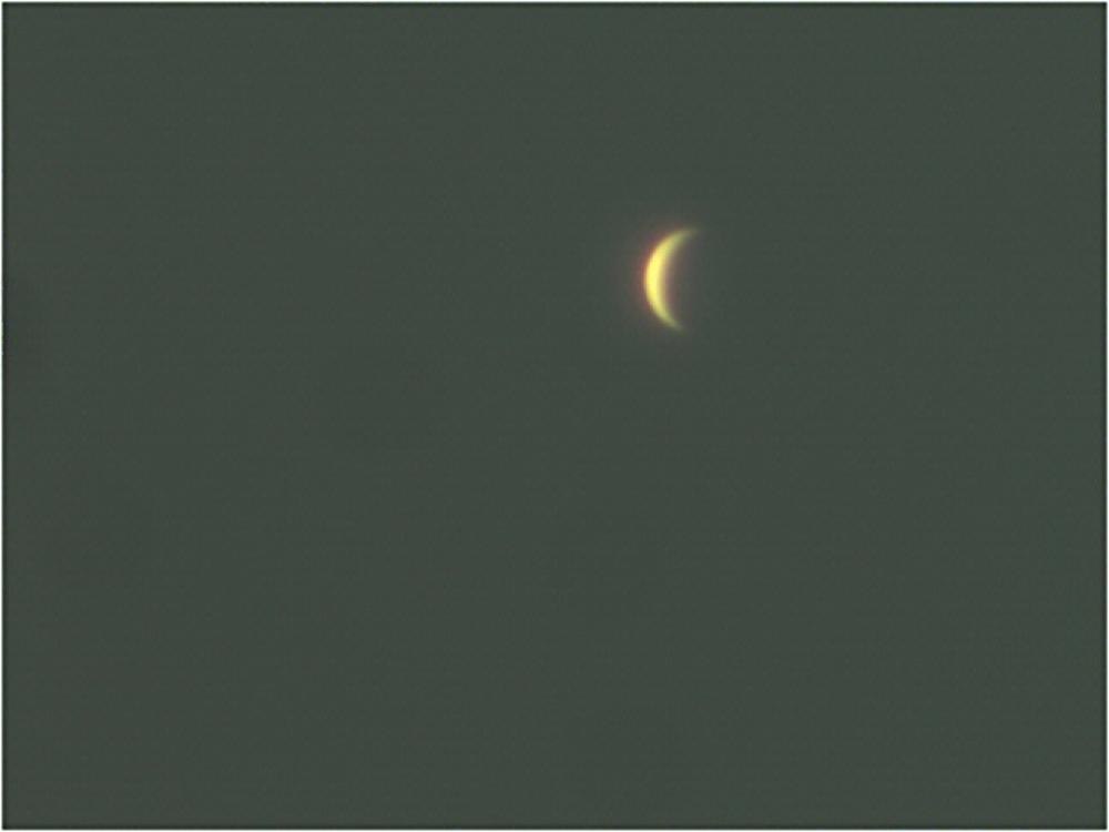 Venus as a waxing crescent shape seen during daytime hours.