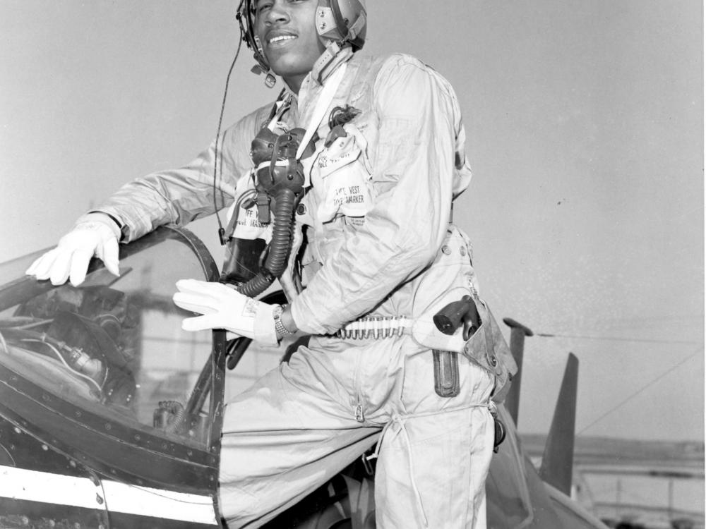 General Frank E. Petersen, an African-American Marines aviator, poses as he steps into a plane. He is wearing pilot gear.