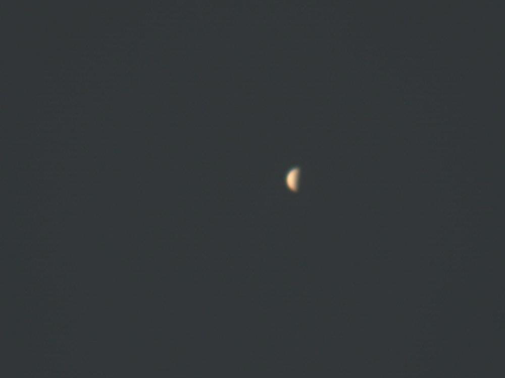 Venus as a half-spherical entity visible from the Earth during daytime hours.