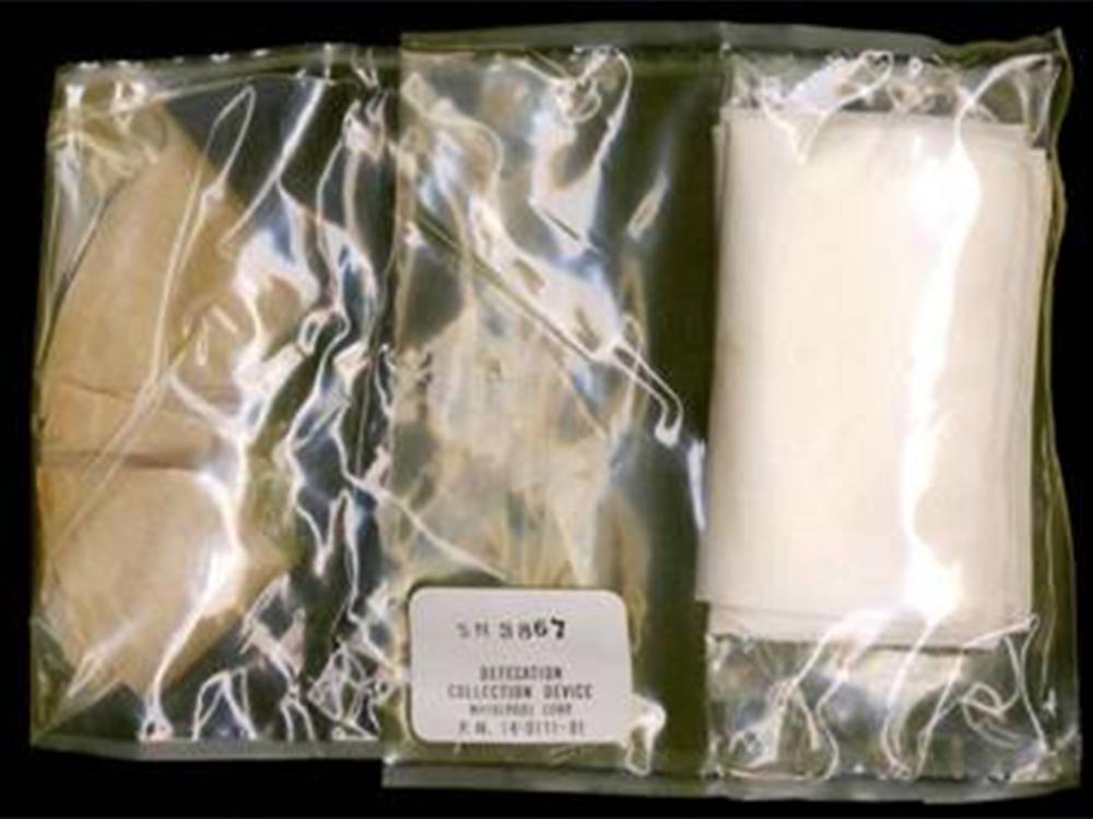 A clear package featuring a fecal collection device and wipes. The outer package is marked for its purpose.