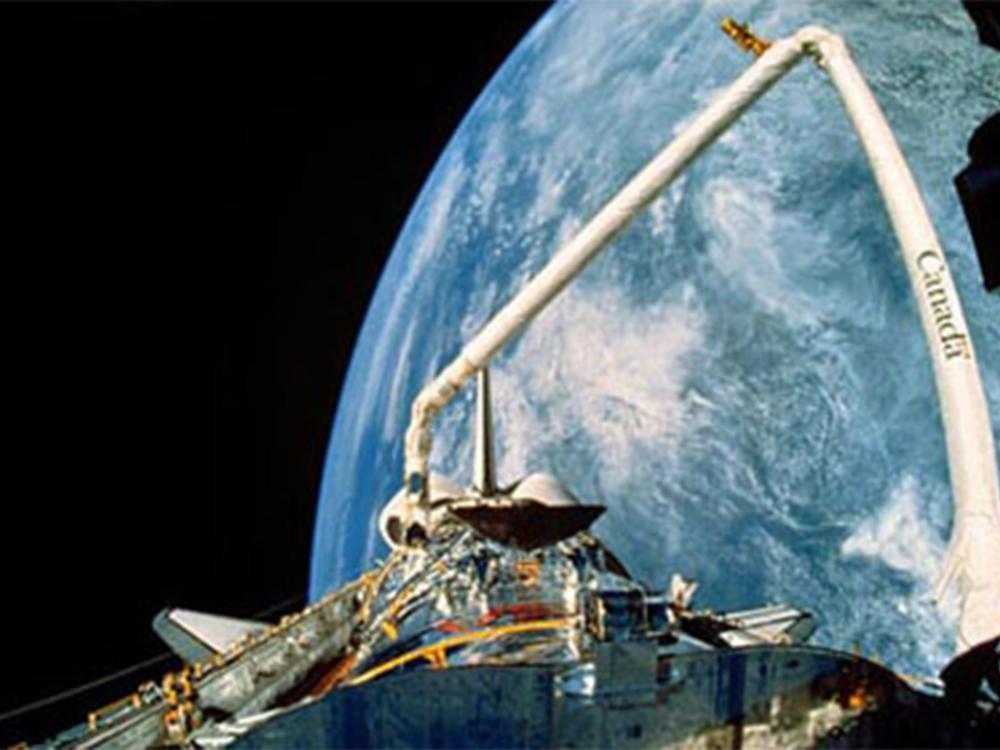 A view of the Hubble Space Telescope's payload bay and Canadarm with the backdrop of Earth.