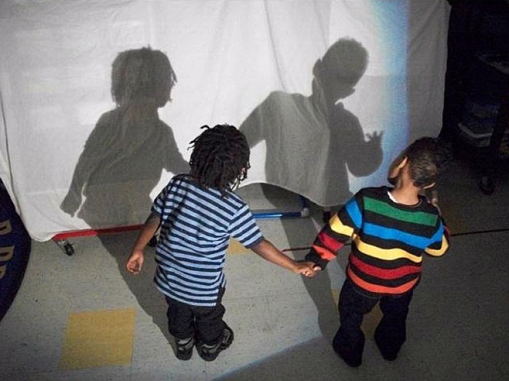 Two small children look at their shadows during a science activity.