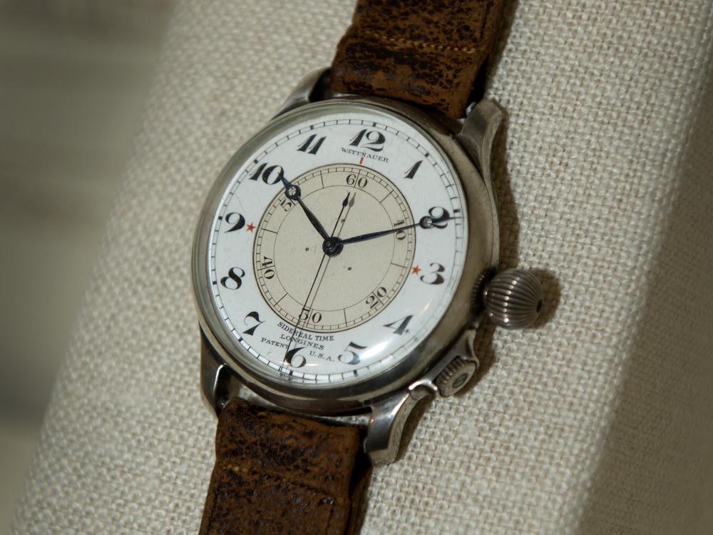 An analog watch with a brown leather watchband.