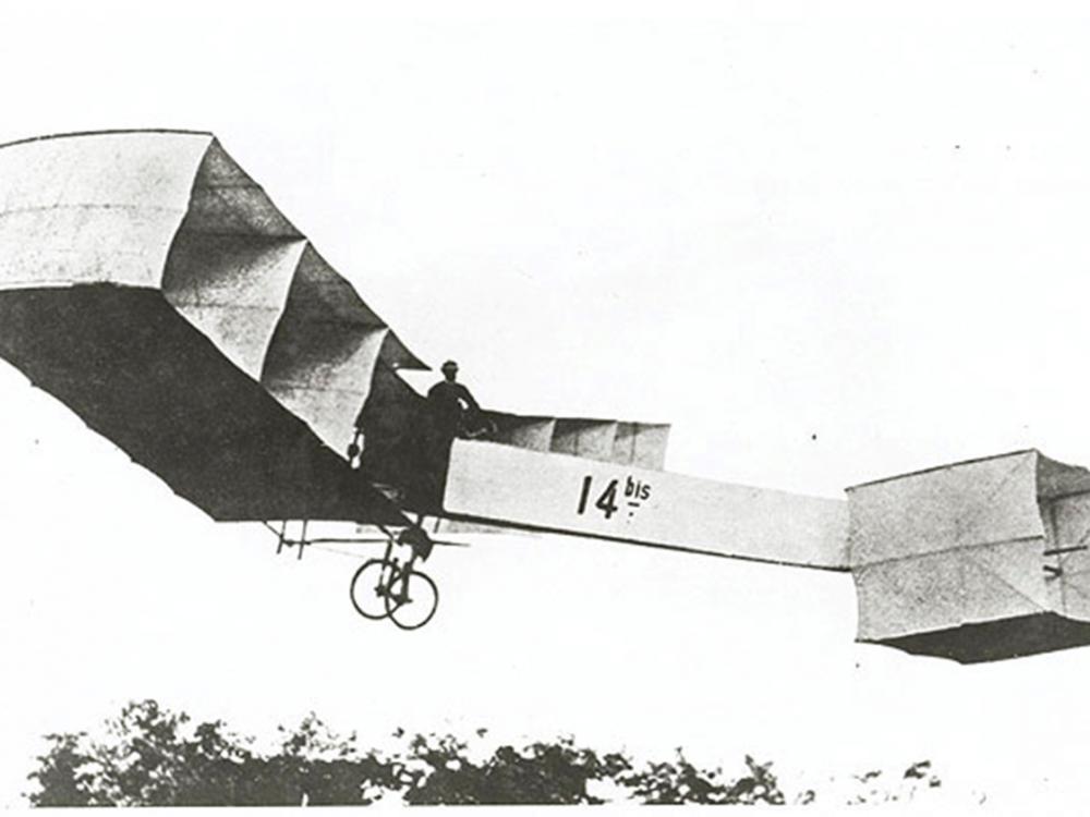 A person flies an early biplane with multiple box-like shapes forming the wings and nose.