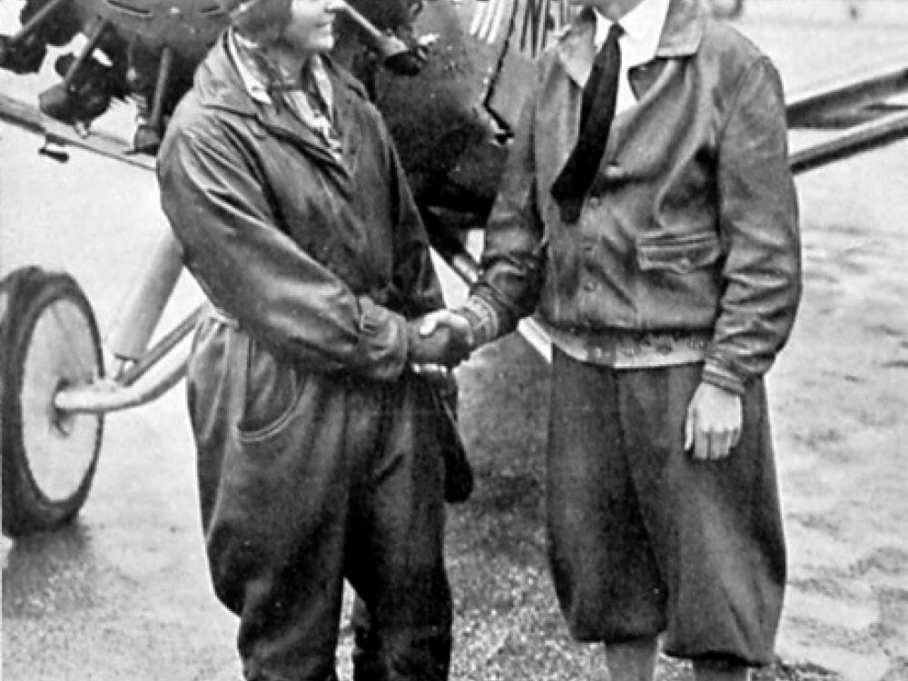 Thea Rasche, a white female pilot, holds hands with Clarence Chamberlin, a white male pilot.