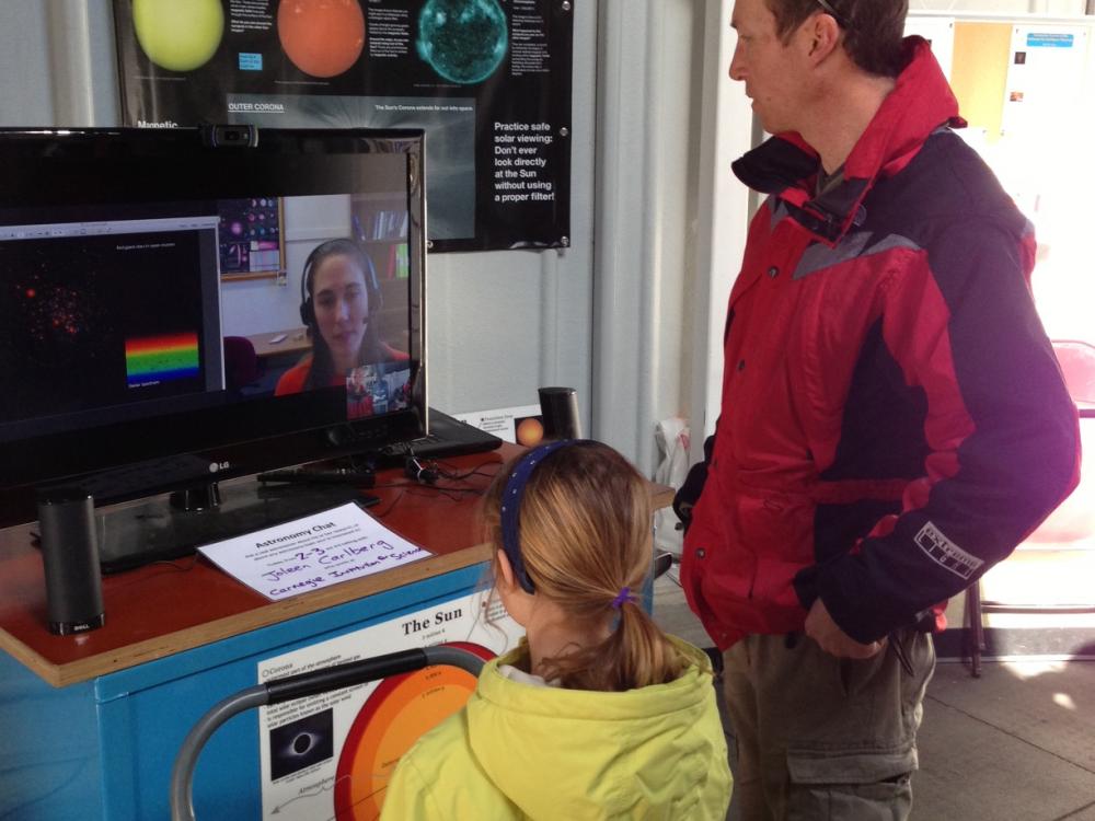 Two visitors speak with an astronomer through video chat in the Museum's observatory.