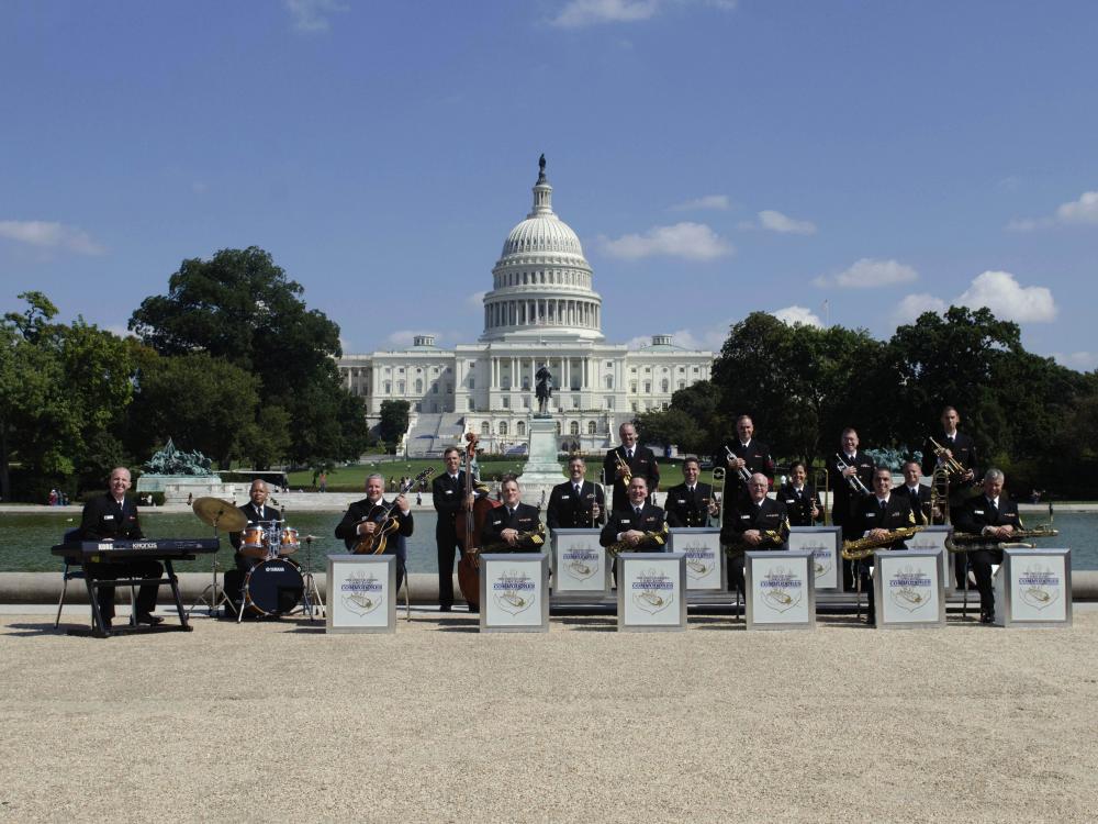 A group of jazz musicians in an ensemble stand outside the U.S. Capitol building.