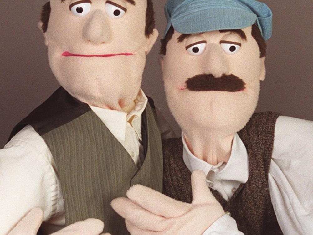 Two puppets dressed as the Wright brothers pose for a portrait.