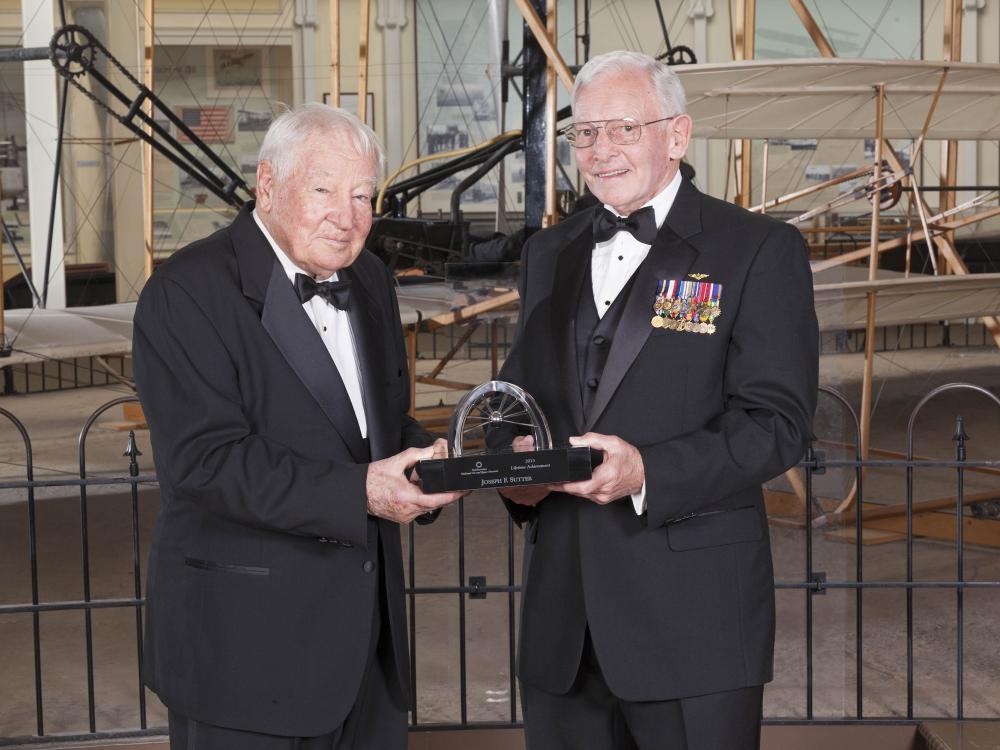 Joseph Sutter and Gen. Jack Dailey, both white men, pose for a photo as Joseph Sutter accepts a trophy.