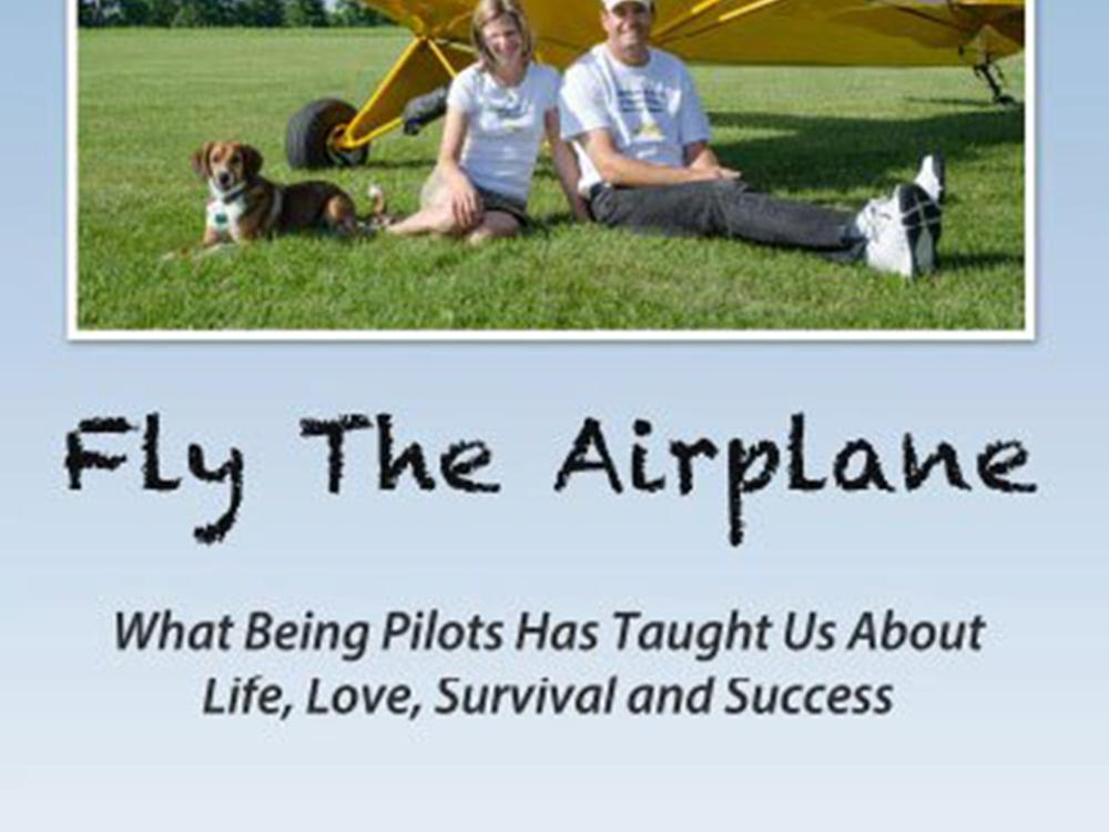 Book cover featuring two people standing below a yellow monoplane. Under the photo the title "Fly The Airplane: What Being Pilots Has Taught Us About Life, Love, Survival, and Success" is revealed.