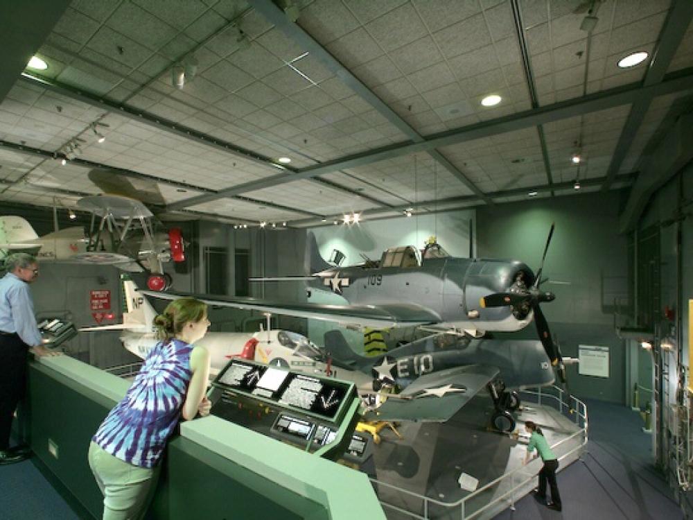 A visitor leans to look closer at an artifact in the Sea-Air Operations Gallery.