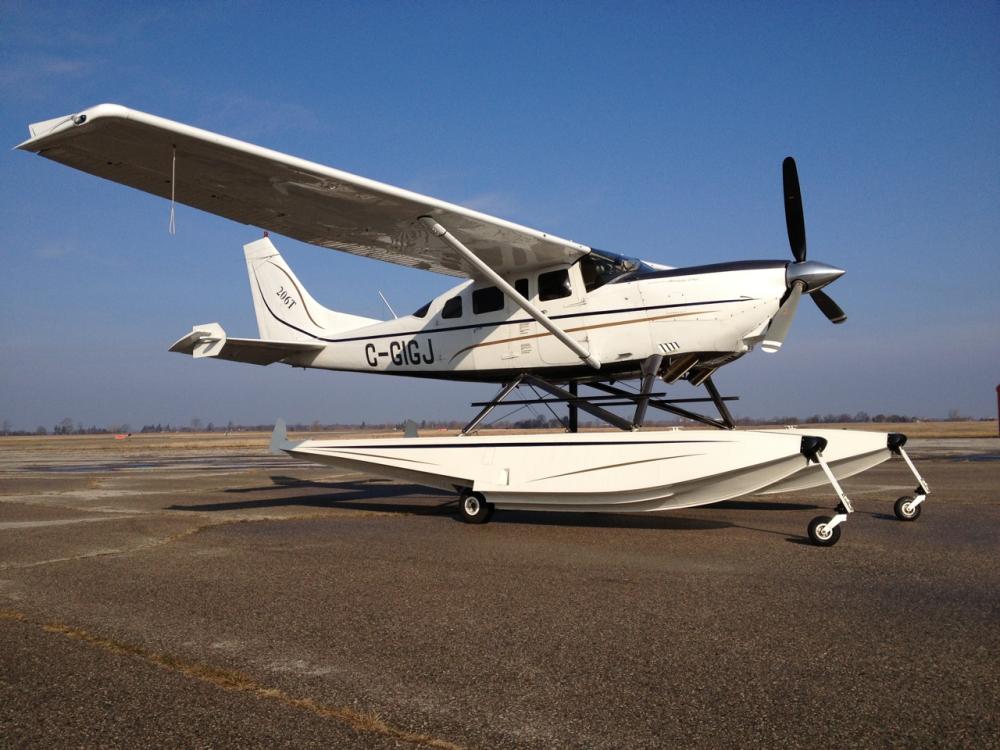 Side view of white amphibian aircraft with fixed floats attached below the cockpit of the aircraft.