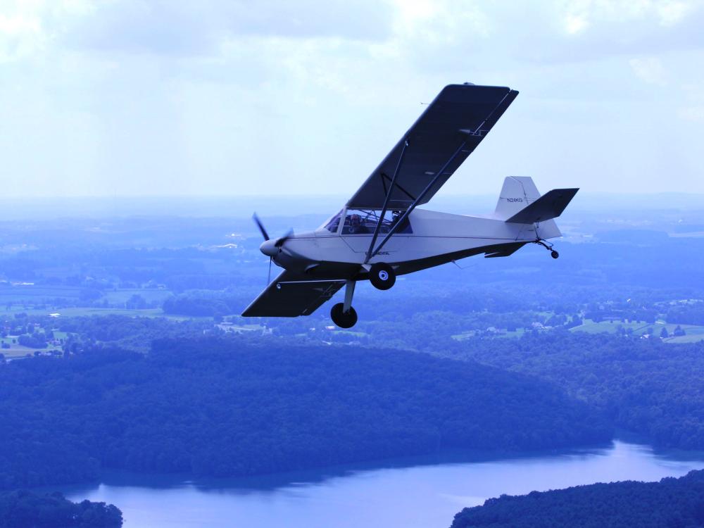 Side view of a white monoplane with one engine in flight. 