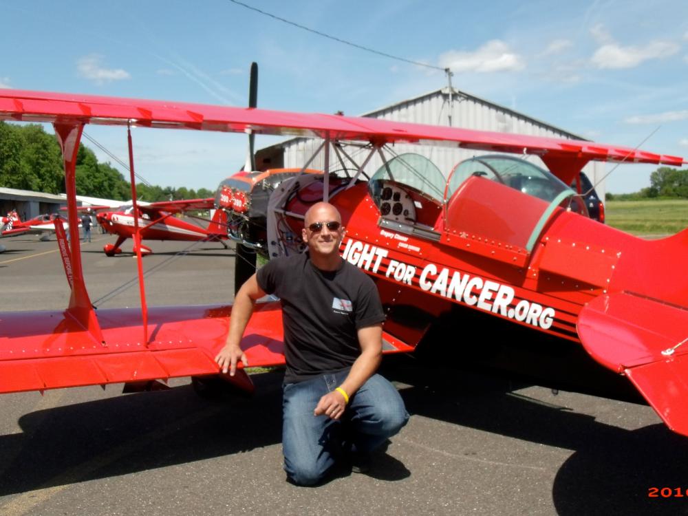 Back view of red biplane with a person standing in front of the wing.