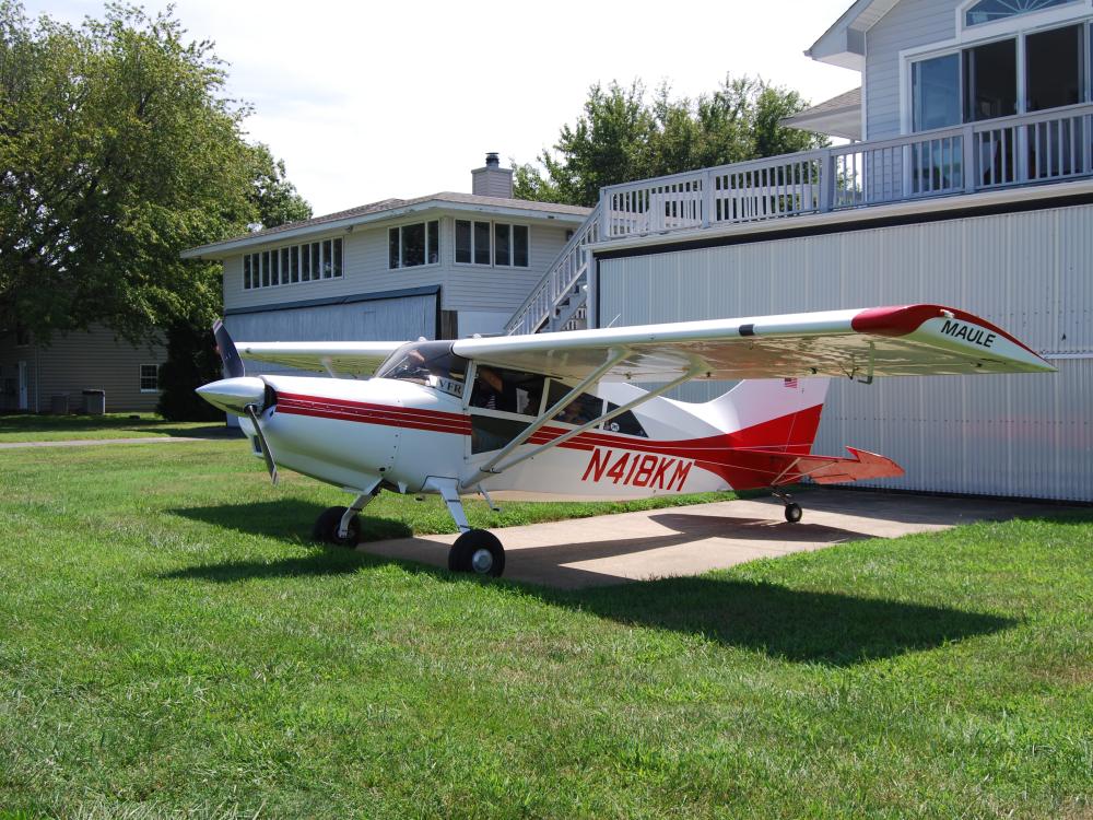 Side view of white and red monoplane with single engine. Registration number N318KM is painted in red near the rear of the fuselage.