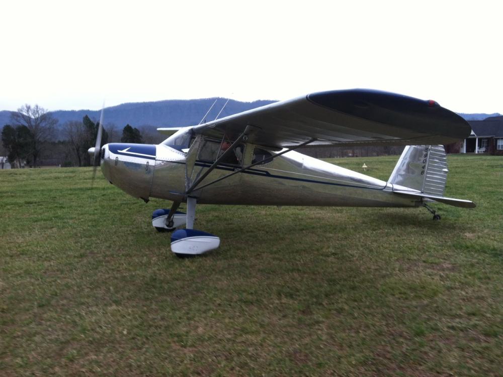 Side view of white and blue monoplane with single engine and fixed landing gear.