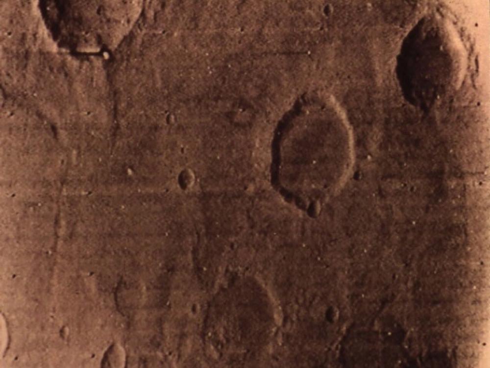 A partial view of Mars from orbit, showing off craters on the surface.