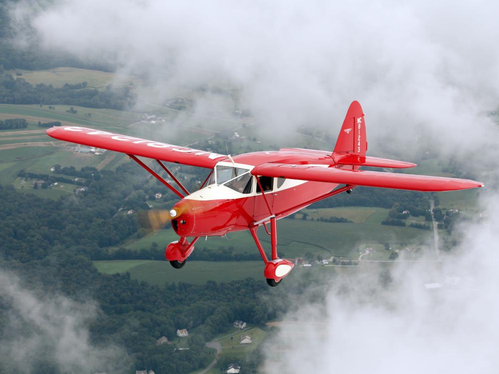 Front view of red and white monoplane with one engine and fixed landing gear.