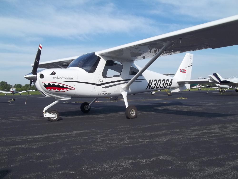 Side view of a white monoplane with a single engine and fixed landing gear. A shark mouth decal is on the front of the cockpit and registration number "N30364" is painted in black near the rear of the fuselage.