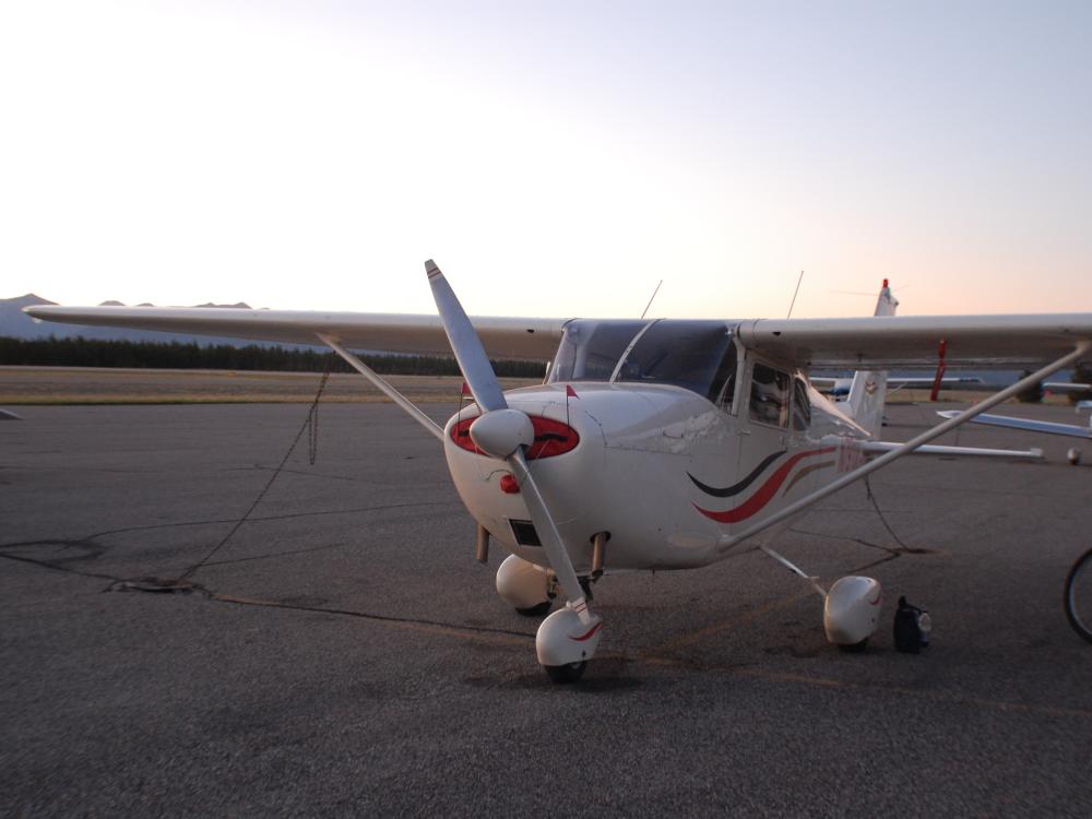 Front view of a white monoplane with a single engine and fixed landing gear.