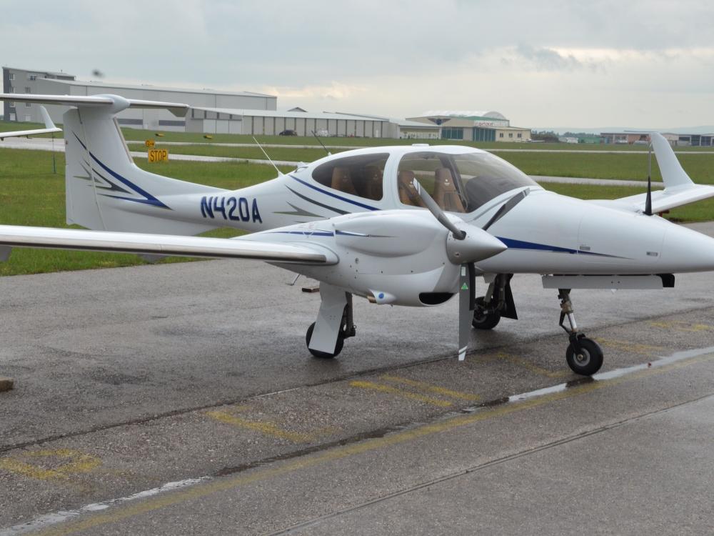 Side view of white and blue monoplane with twin engines. Registration number "N420A" is painted in blue near the rear of the fuselage.