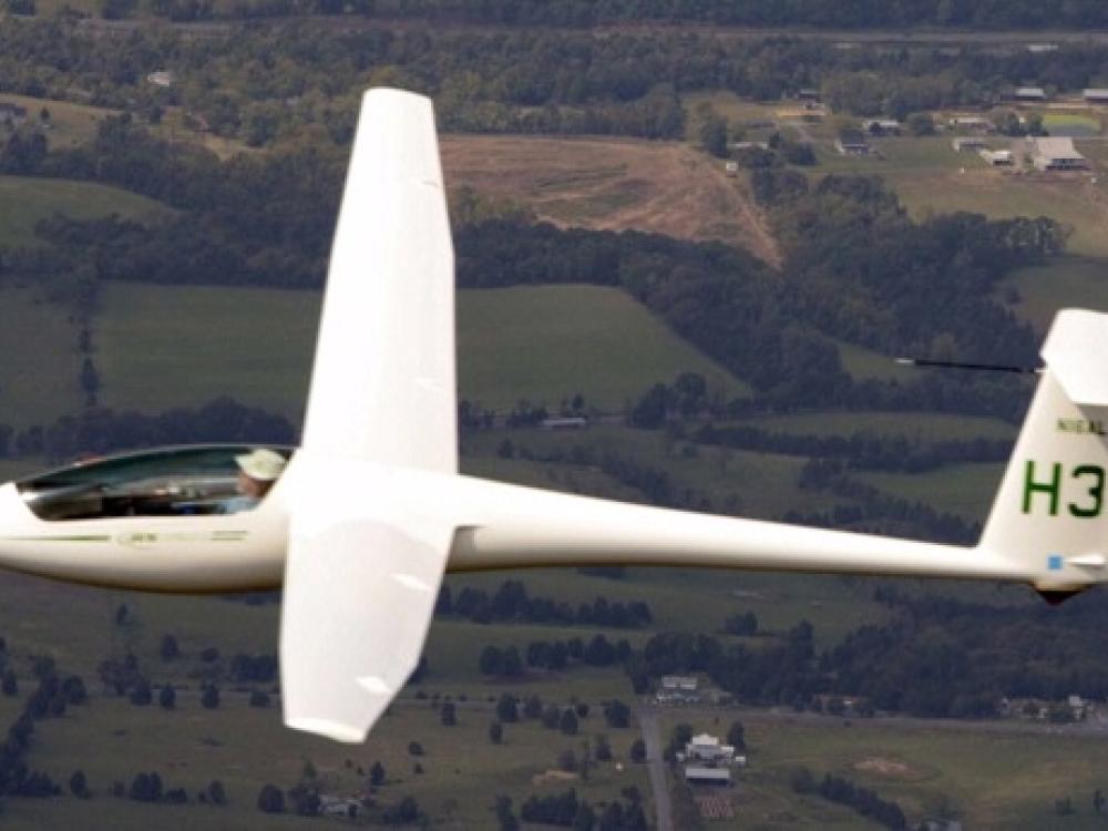 Side view of white glider aircraft with notably long wings.