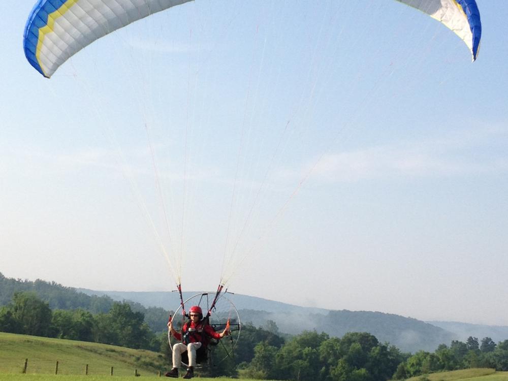 Front view of one-person paraglider with blue, yellow, and white fabric.