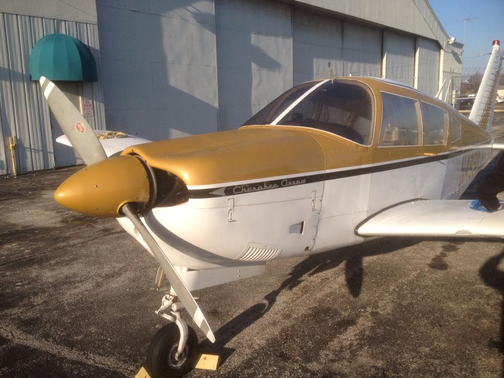 Front view of gold-colored and white aircraft focusing on the nose and single engine. 