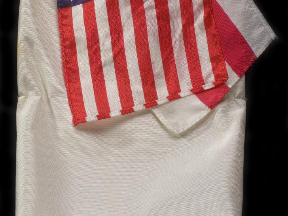 Small red, white, and blue United States flag on top of a white bag.