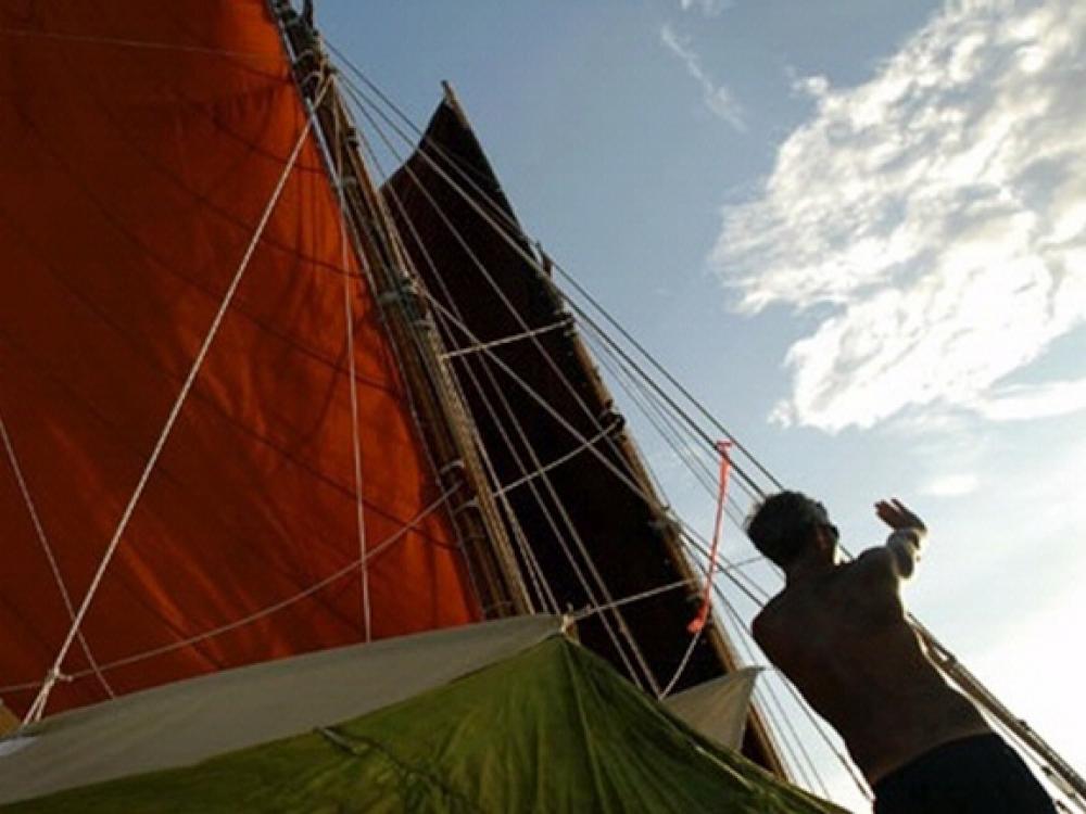 A person on a sailboat uses their hands to determine direction.