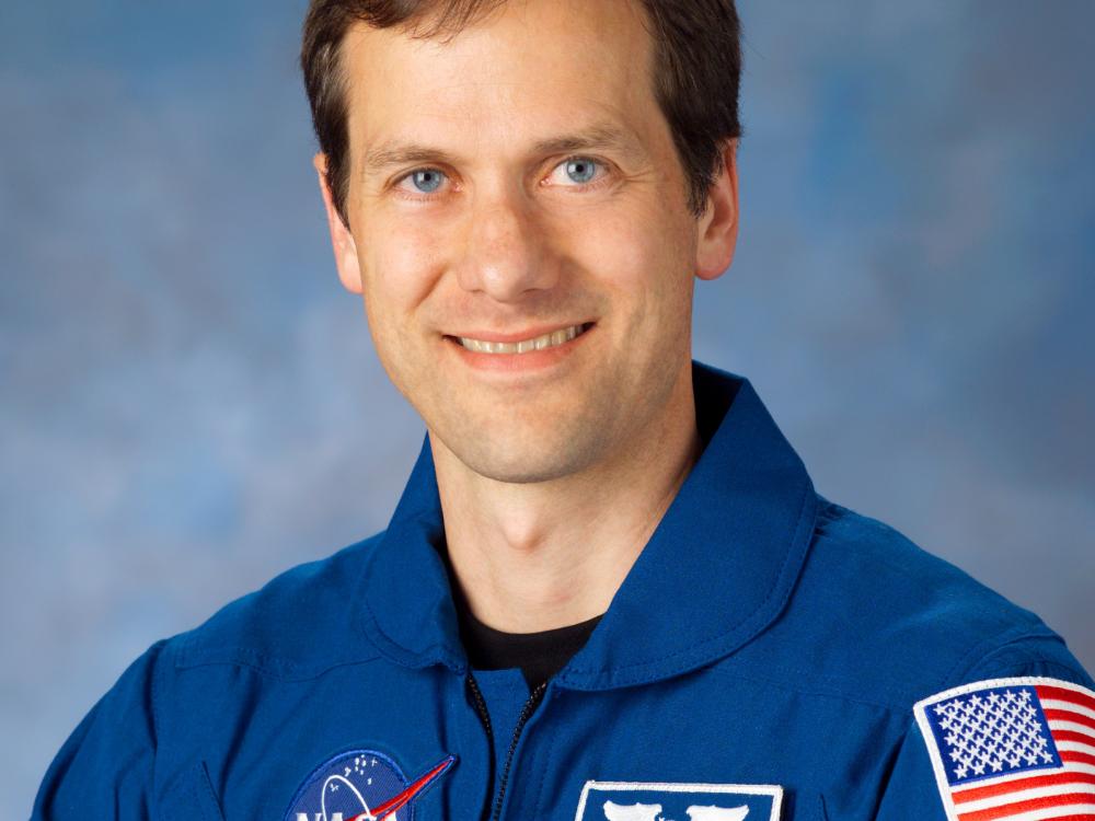 Dr. Thomas Marshburn, an astronaut, sits for an official portrait wearing blue NASA flight gear.