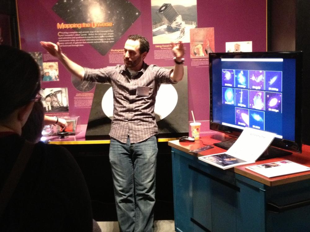 A museum expert discusses astronomy with visitors inside a museum gallery.